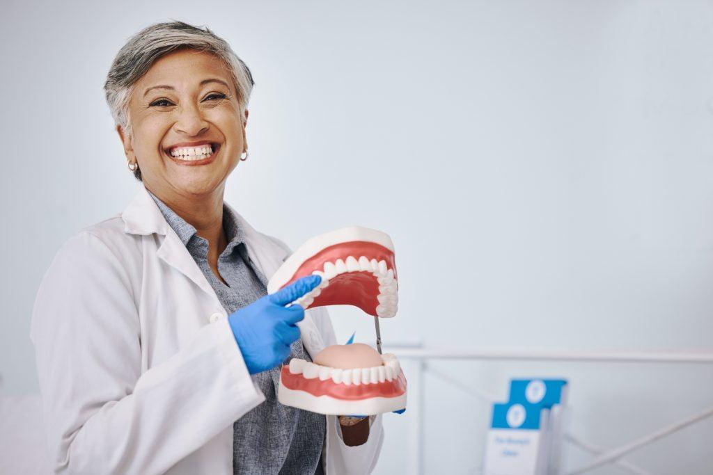 dentist-dentures-portrait-senior-woman-dentistry-medical-dental-service-clinic-healthcare-happy-female-worker-point-mouth-mold-oral-health-teeth-cleaning-cavity-scaled