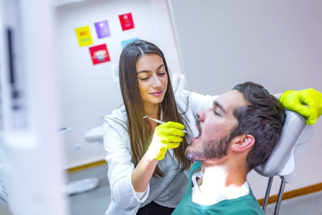 doctor-doing-dental-treatment-man-s-teeth-dentists-chair-scaled