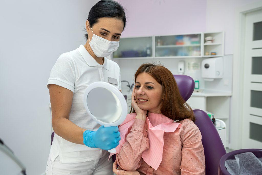 female-dentist-observes-satisfied-patient-who-is-happy-after-treatment-teeth-whitening-healthy-teeth-woman-joy-dentist-s-office-scaled