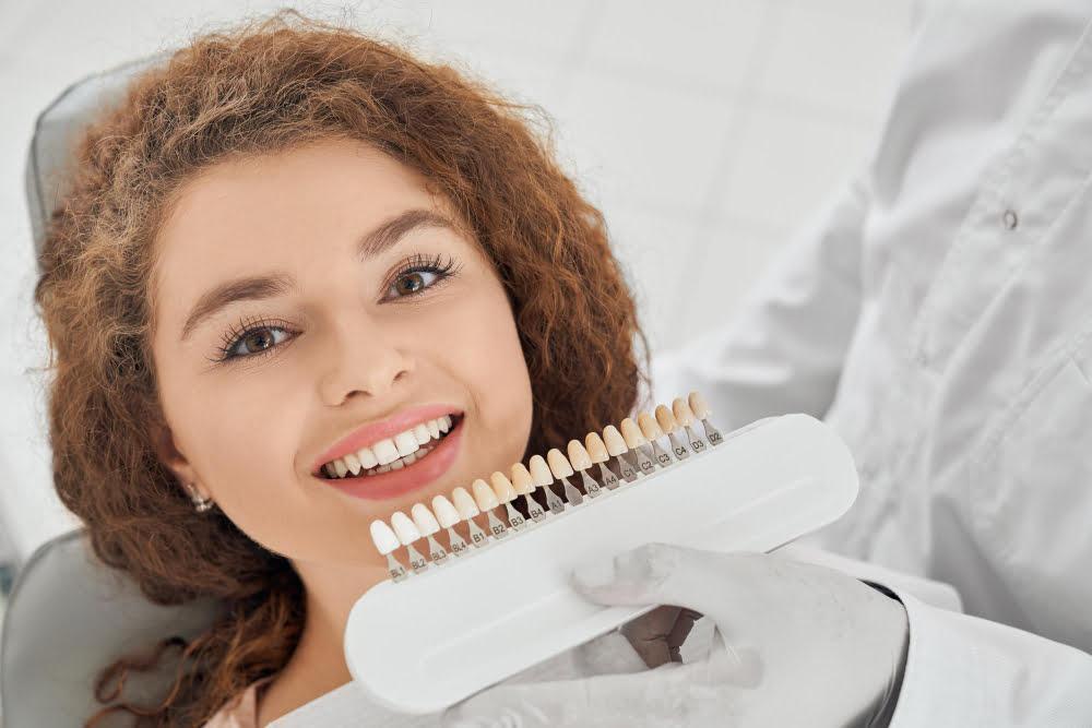 woman-smiling-while-male-dentist-keeping-teeth-color-range