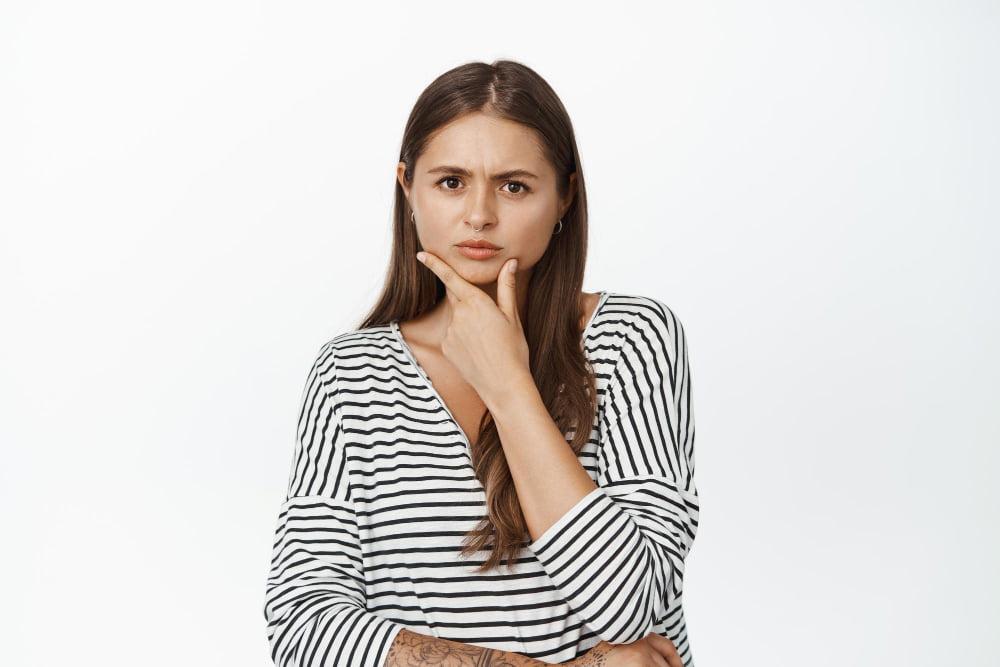 young-woman-thinking-having-doubts-looking-serious-camera-with-fingers-touching-chin-ponder-decision-white-background