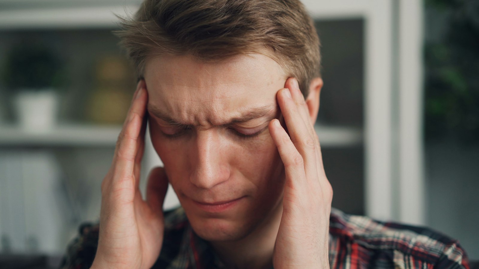 Man holding his temples from sinus tooth pain during allergy season